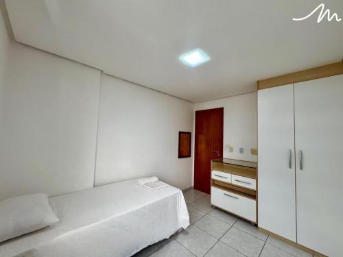 a bedroom with a white bed and a cabinet at Tambaú Home Service - Miramar Hospedagens in Tambaú