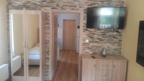 een slaapkamer met een bed en een televisie aan een bakstenen muur bij Stacja Roman in Karpacz