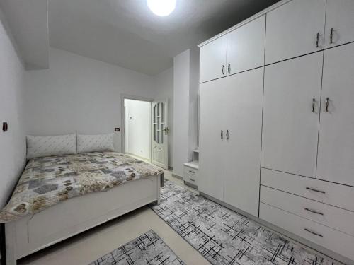 une chambre blanche avec un lit et des armoires blanches dans l'établissement Minga Apartments, à Pogradec