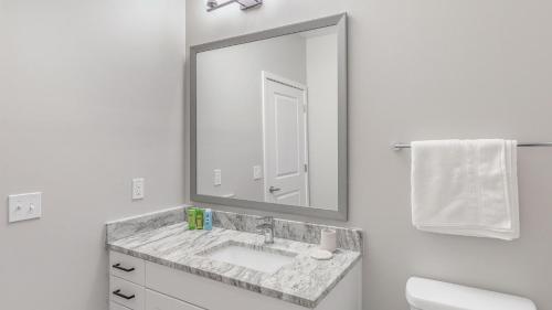 a white bathroom with a sink and a mirror at Landing Apartments Dry Creek - Huntsville in Huntsville