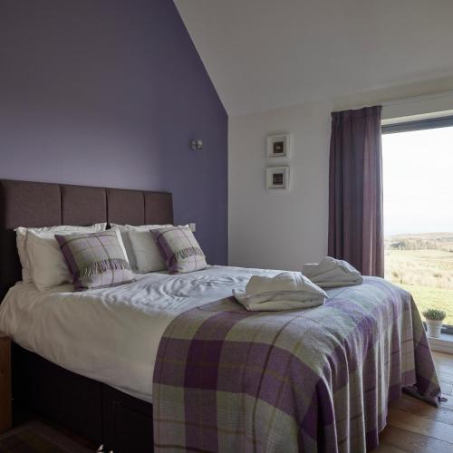 a bedroom with a bed with a blanket and a window at Skye Eyrie in Staffin