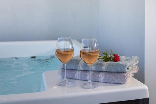 two glasses of wine sitting on a table next to a swimming pool at Aphrodite's Refuge in Galissas