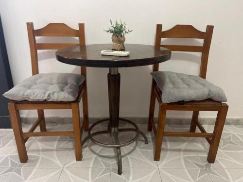 una mesa de madera con 2 sillas y una mesa con una planta. en Aura Rooms, en Durrës