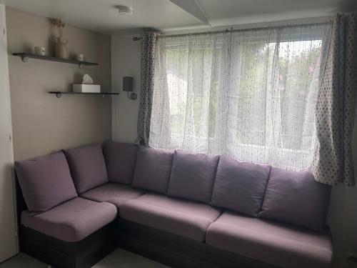 a purple couch sitting in front of a window at Mobil home 6 personnes in Les Mathes