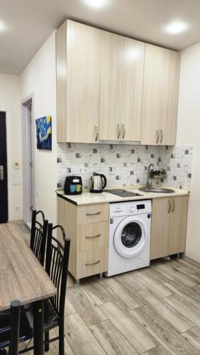 a kitchen with a washing machine and a table at Ande Tower, Batumi in Minda
