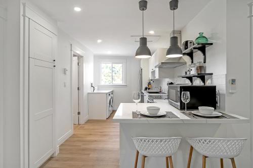 a white kitchen with two chairs and a counter at 1BR Bluebird Retreat in Peterborough