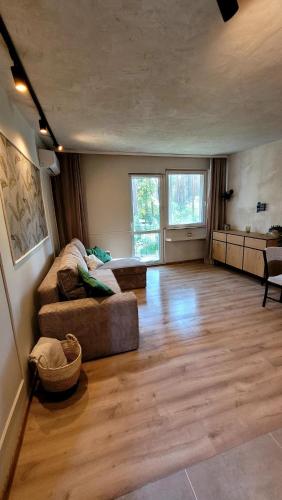 a living room with a couch and wooden floors at Leśne Apartmani Biała in Biała