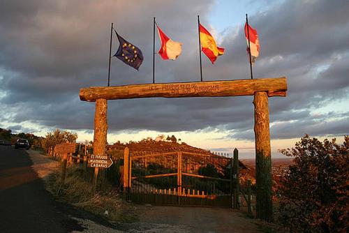 a wooden sign with flags on the side of a road at El Mirador de la Mancha in Villarrubia de los Ojos