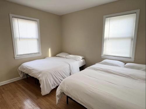 two beds in a room with two windows at Cheerful 3-Bedroom Apartment in Valley Stream