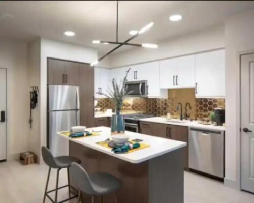 a kitchen with white cabinets and a kitchen island with chairs at Cozy 2bd Apt Near Disneyland Anaheim Conv Center in Anaheim