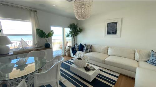 オーモンド・ビーチにあるLuxury Ormond Beach Condoのリビングルーム(白いソファ、ガラスのテーブル付)
