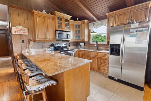 Una cocina con gabinetes de madera y un refrigerador de acero inoxidable. en 5005 - Bristow`s Bungalow, en Kill Devil Hills