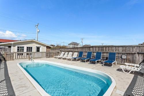 a swimming pool with lounge chairs and a fence at 6175 - Longview Cottage in Whalebone