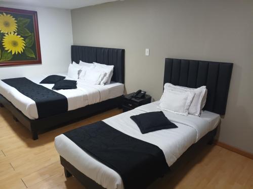 two beds in a hotel room with black and white at Hotel Santiago Plaza in Bogotá