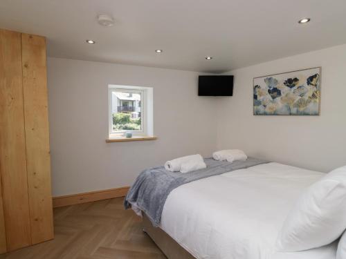 une chambre blanche avec un lit et une fenêtre dans l'établissement Old Post Office Cottage, à Ulverston