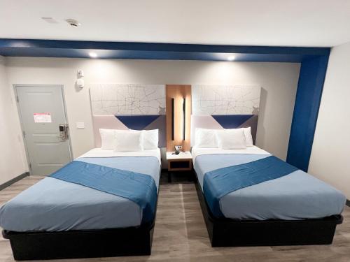 two beds in a room with blue and white at Crystal Inn - NorthWest - 290 in Houston