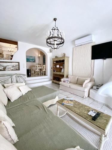 a living room with a couch and a chandelier at Hébergement cycladique - près de Panormos in Mykonos