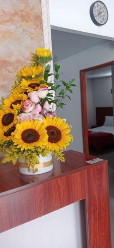 a vase filled with yellow flowers on a table at Hotel el cable pereira in Pereira