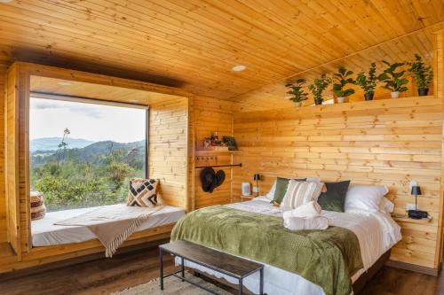 a log cabin bedroom with a bed and a window at La Dolce Vita, Guatavita in Guasca