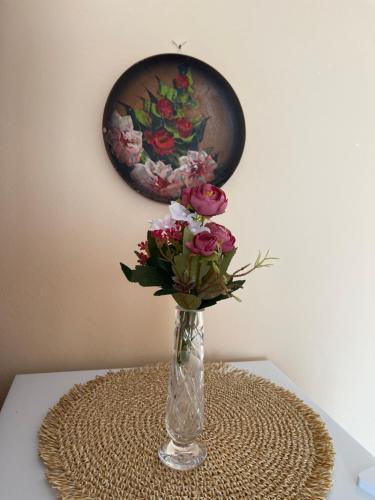 a vase of flowers on a table with a painting at 4 Roses Residence in Sečovlje