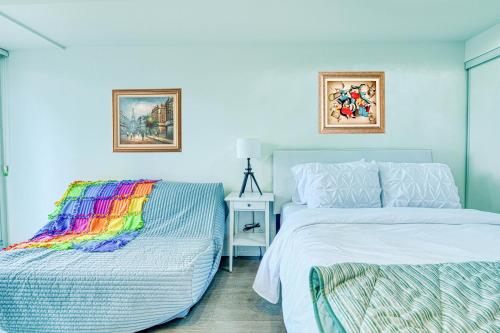 a bedroom with two beds and a rainbow blanket at RivetStays - The Jarvis in Toronto