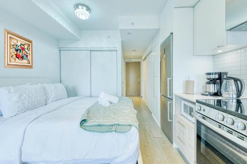 a white bedroom with a bed and a kitchen at RivetStays - The Jarvis in Toronto
