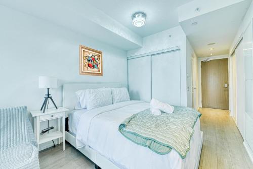 a white bedroom with a bed and a night stand at RivetStays - The Jarvis in Toronto