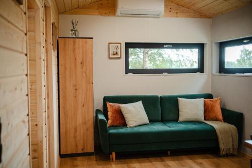 a green couch in a room with two windows at Domek Księża Góra in Krasnobród