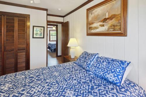 a bedroom with a blue bed and a picture on the wall at 2029 - Duck Yeah in Duck