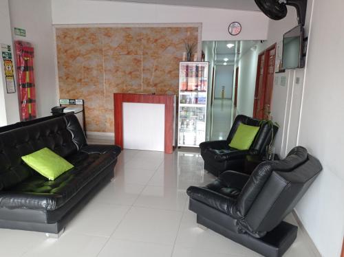a living room with two black leather couches at Hotel el cable pereira in Pereira