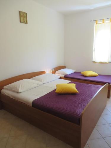 two beds in a room with purple sheets and yellow pillows at Apartments Luka in Pakoštane