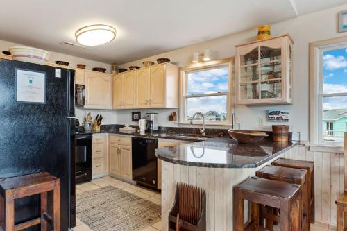 a kitchen with wooden cabinets and a black refrigerator at 3014 - Endless Horizons in Duck