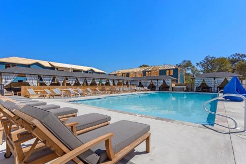 a swimming pool with chaise lounge chairs in a resort at BCW30A - Waves Inn in Corolla