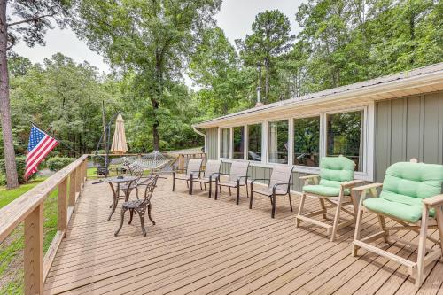 a wooden deck with chairs and tables and a flag at Treetop Hideaway with Lake Views and Fire Pit! in Fairfield Bay