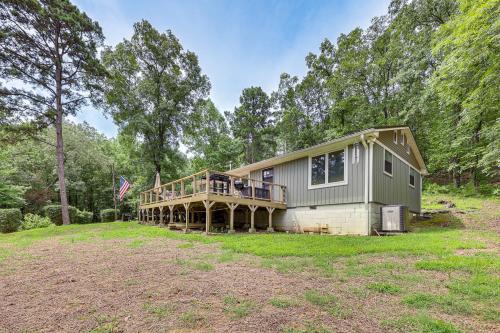 a house with a wrap around deck in a field at Treetop Hideaway with Lake Views and Fire Pit! in Fairfield Bay