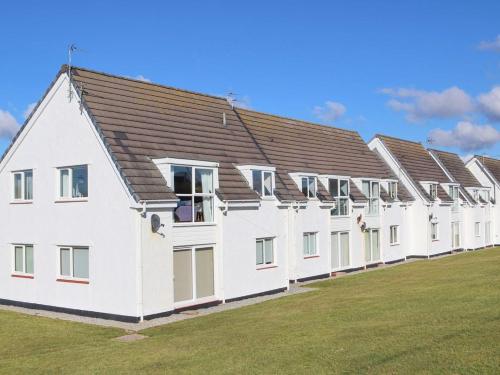 a row of white buildings on a grass field at Apartment in Treardurr Bay