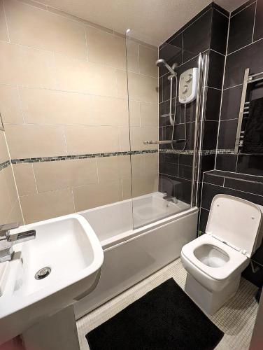 a bathroom with a sink and a toilet and a bath tub at Apartment in Treardurr Bay