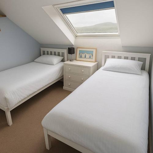 two beds in a bedroom with a skylight at Apartment in Treardurr Bay
