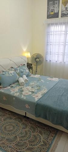 a bedroom with a bed with a blue blanket and a window at Homestay Cikgu-formuslimonly in Pasir Gudang