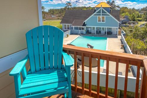 a blue rocking chair on a balcony with a swimming pool at CP100A - Sound Sunset in Kill Devil Hills