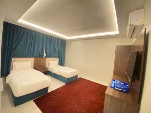 a small room with two beds and a flat screen tv at فندق منازل روز in Al Lith