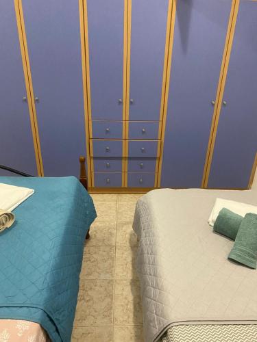 a bedroom with two beds and a blue wall at Sunset Villa Apartments Alepokhori in Káto Alepokhórion