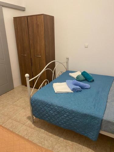 a bedroom with a bed with blue sheets and a wooden cabinet at Sunset Villa Apartments Alepokhori in Káto Alepokhórion