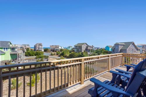 two blue chairs on a deck with a view of the ocean at 8305 - The Sound of Sunshine in Avon