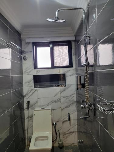 a bathroom with a toilet and a window and a shower at Caesar's Hotel & Apartment Room #14 in Ikeja