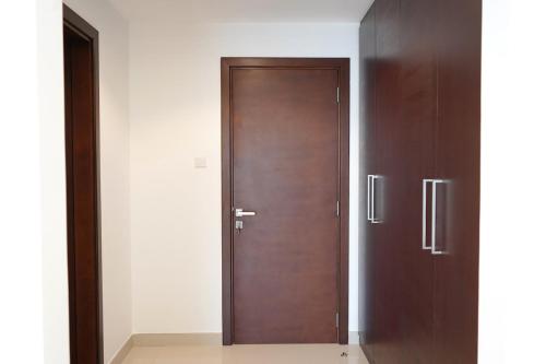 a wooden door in a room with white walls at Al Dana Sea Luxury Villa Fujairah in Sharm