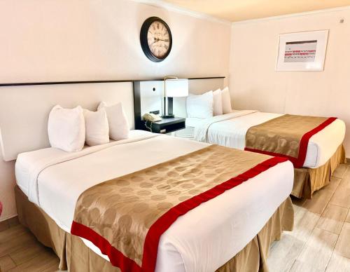 a hotel room with two beds and a clock on the wall at Ramada by Wyndham Birmingham Airport in Birmingham