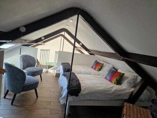 a bedroom with a bed and two chairs at Nant Melyn Farm Apartment in Neath