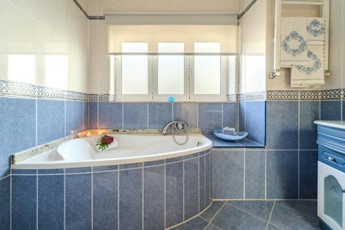 una vasca da bagno in un bagno con piastrelle blu di Casa Ar-Belo by House and People 
