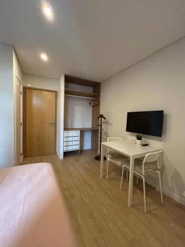 a room with a bed and a table with a television at Porbálio Oporto & Maia Center #1 in Leça do Balio
